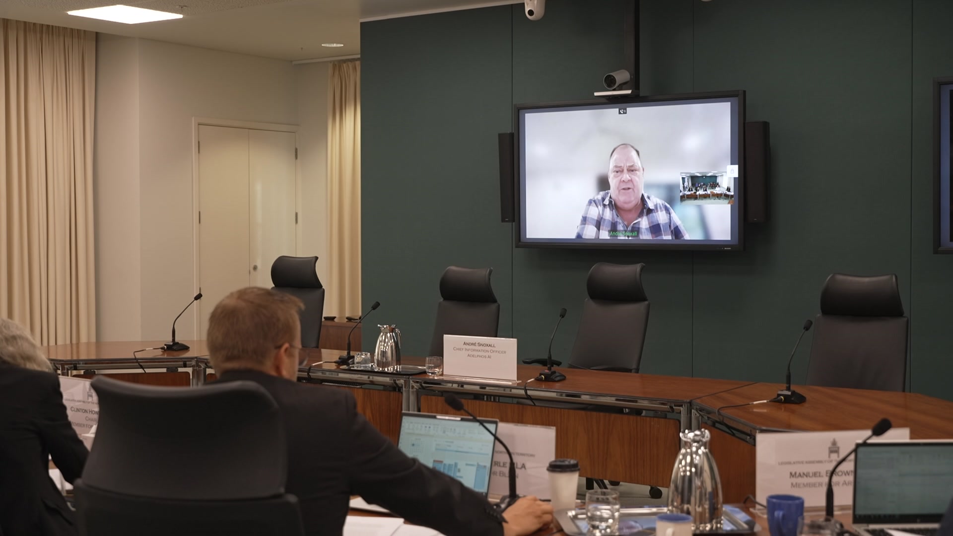 Un hombre en una llamada de Zoom en la televisión en medio de la sala de juntas 