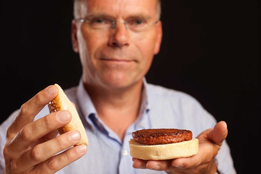 Professor Mark Post holds lab grown patty on a bun