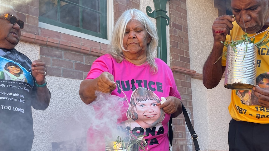 An elderly Indigenous woman is smoking leaves