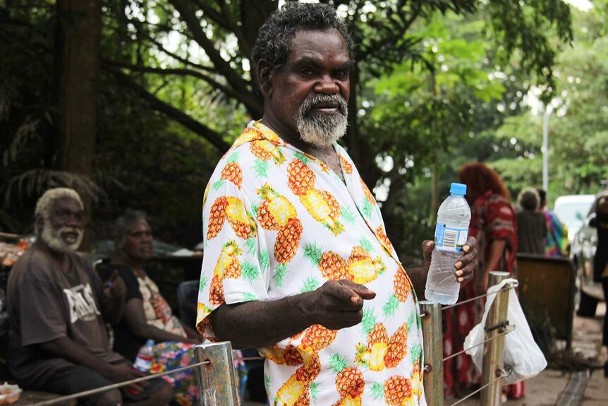 A photo of a of an Indigenous man holding a bottle of water.