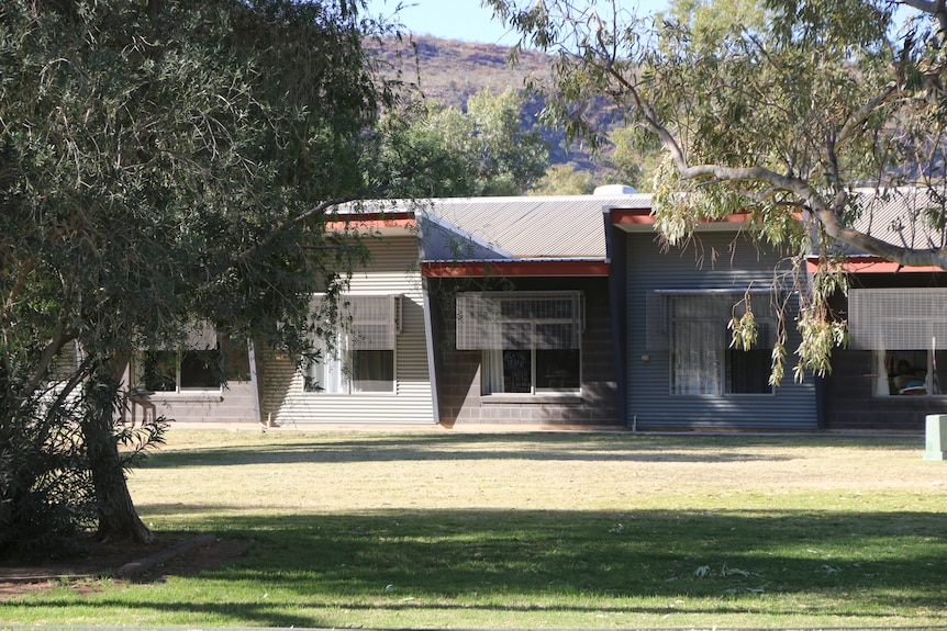 The outside of an aged care centre. Awnings on windows, which look over a grassed area with trees.