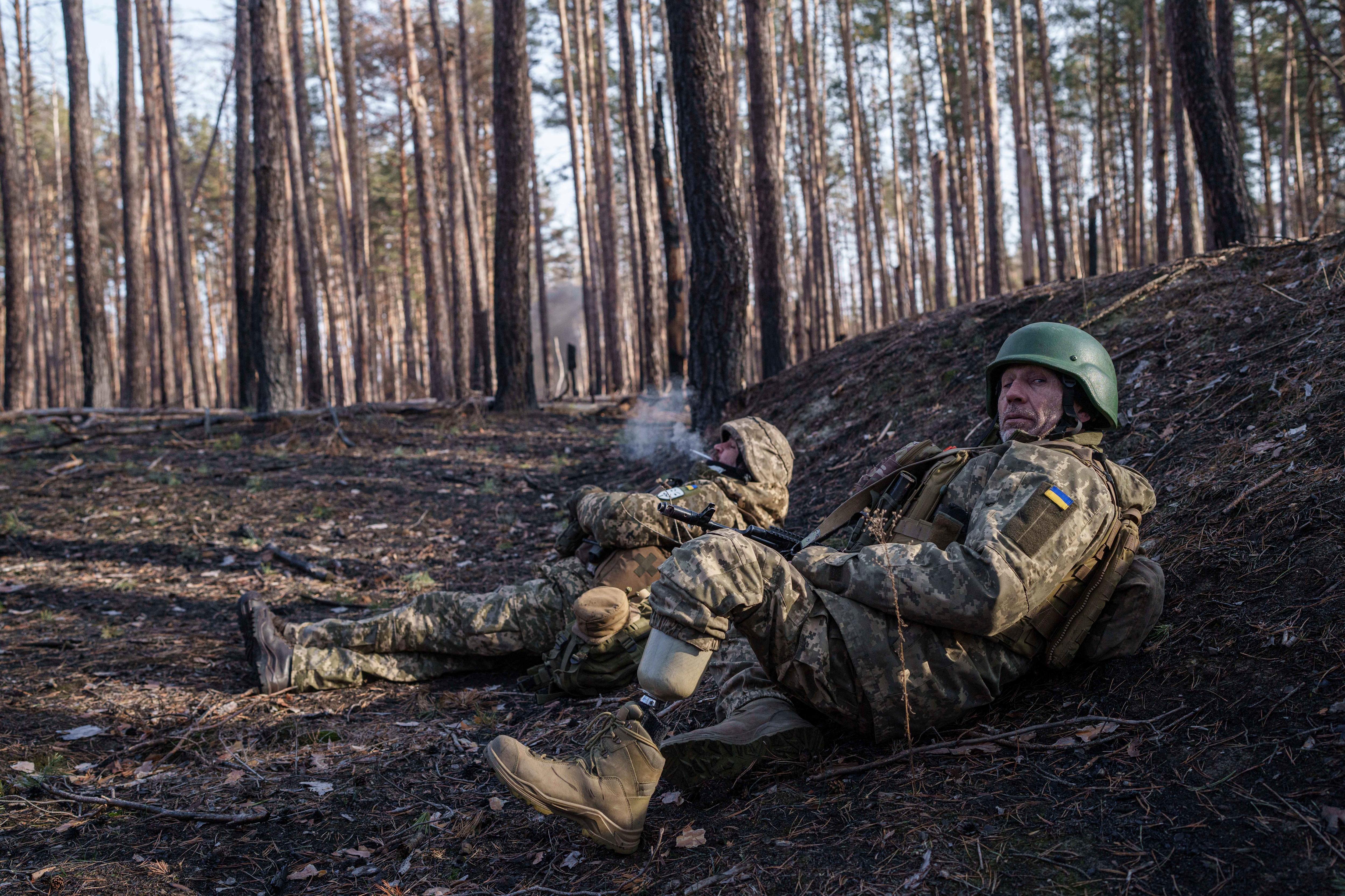 Two soldiers lying in a forest, smoking 