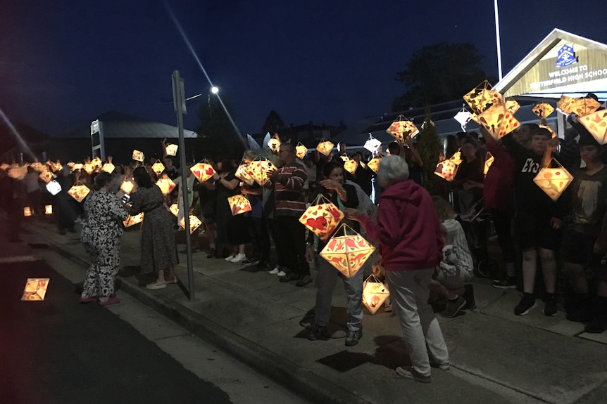 A crowd of people holding lanterns.