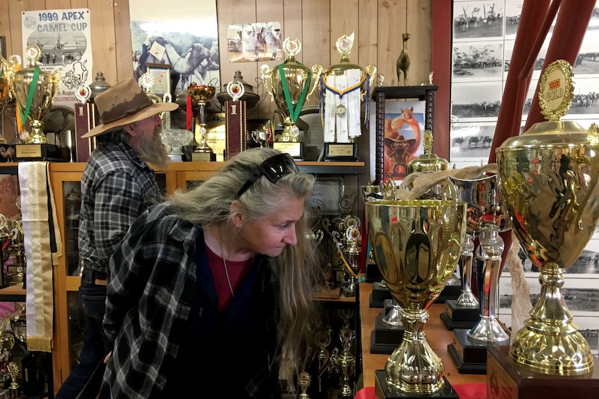 Camel cup riders looking at a collection of their trophies.