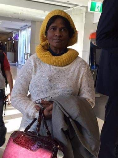 Woman wearing a yellow knitted scarf, jumper and holding a red leather bag.
