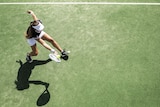 A woman wearing a white hat plays tennis on a green court.