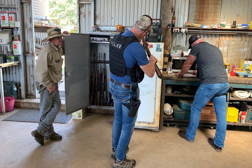 Police examine guns from a cabinet in a farmer's shed.