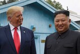 President Trump smiling at Kim Jong-un smiles and looks away
