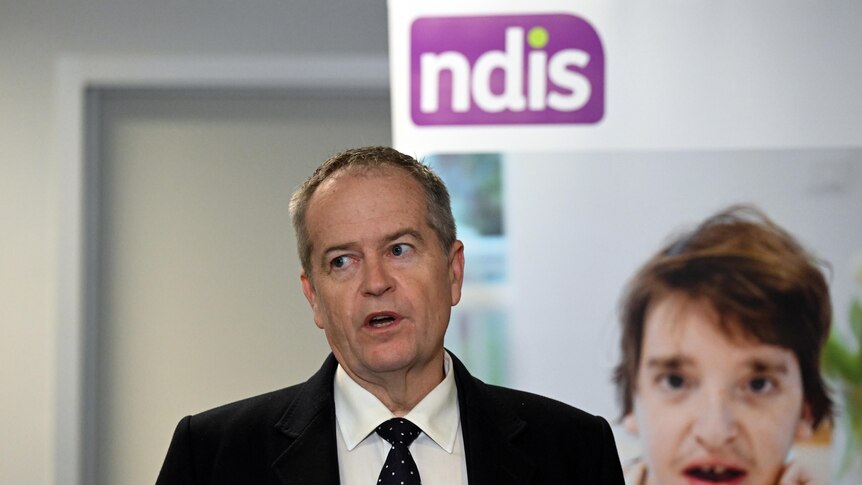 A man in a suit with an NDIS sign