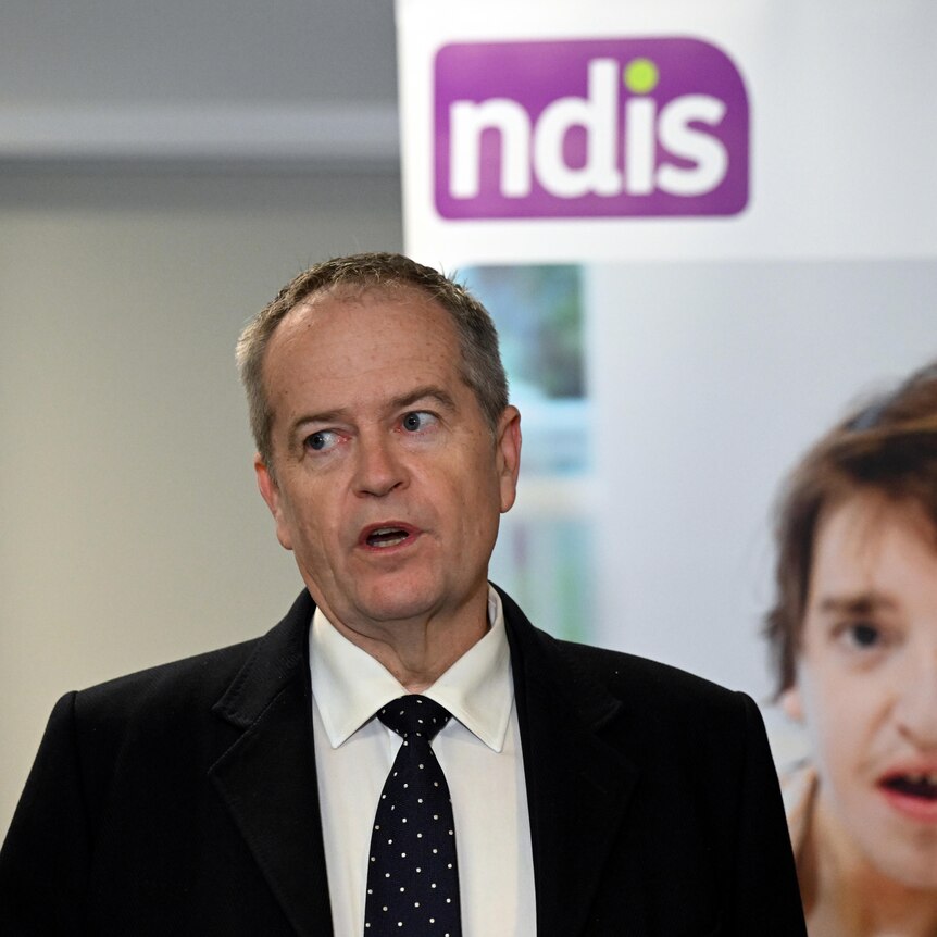A man in a suit with an NDIS sign