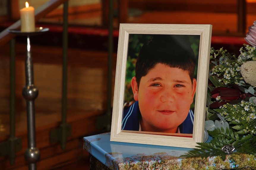 The photo of a young boy on top of a coffin.
