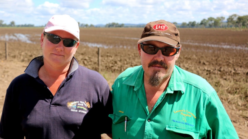 Tracey and Jason Larsen stand in front of one of their ruined mungbean crops on their 1,500 acre property at Monto