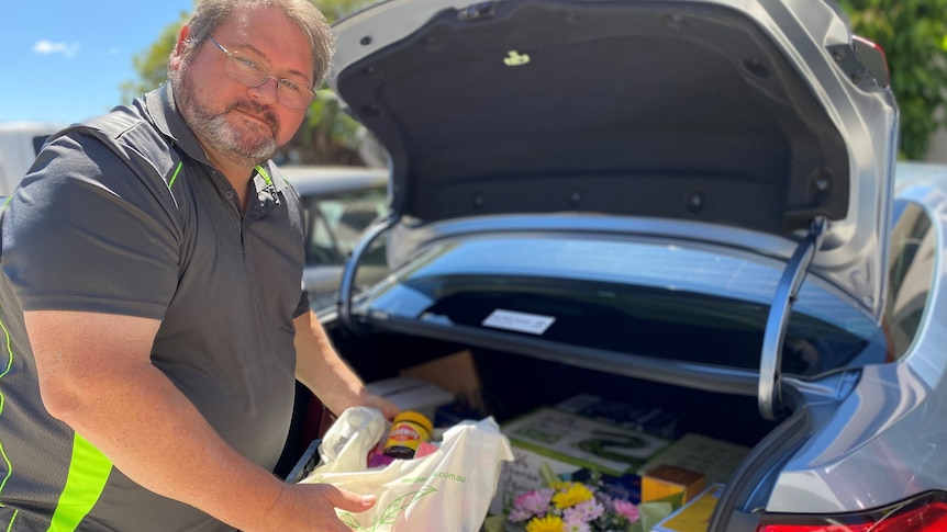 Jonathyn placing flowers and groceries in the boot of his car