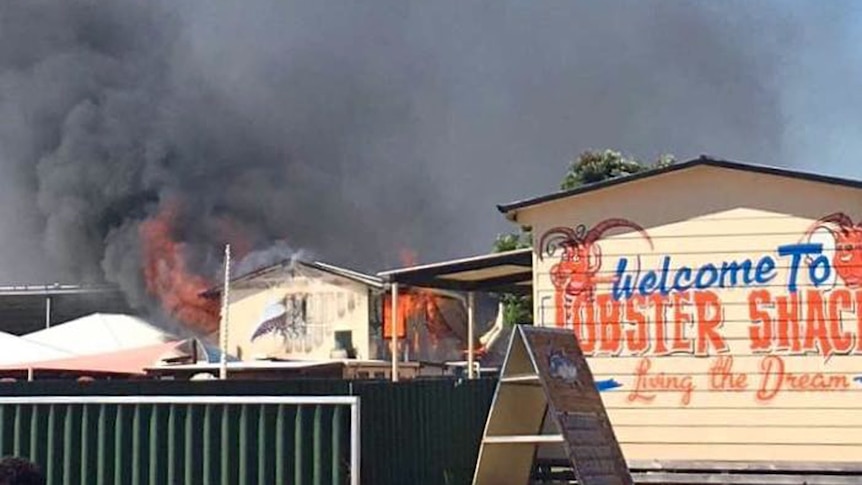 Flames and black smoke at the back of two buildings one with the sign Welcome to the Lobster Shack
