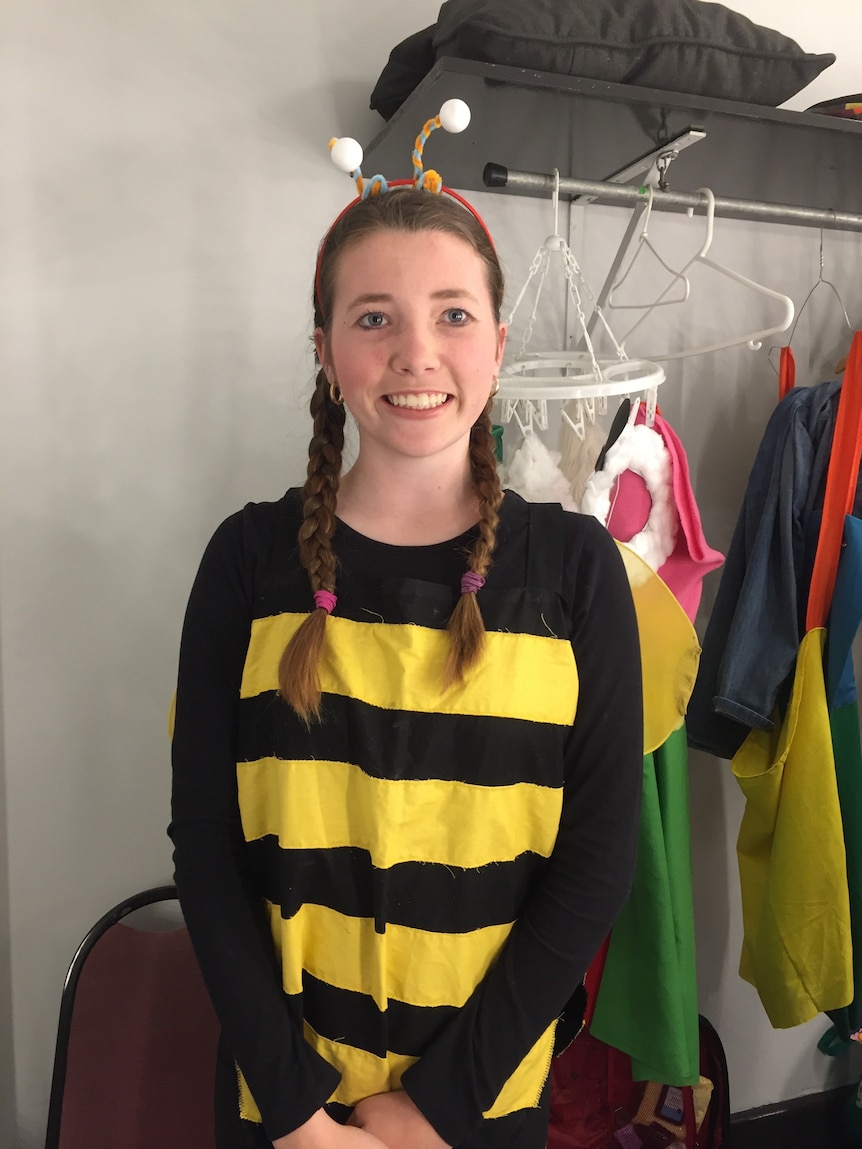 A smiling older teenage girl wearing a bee outfit for a theatre production.