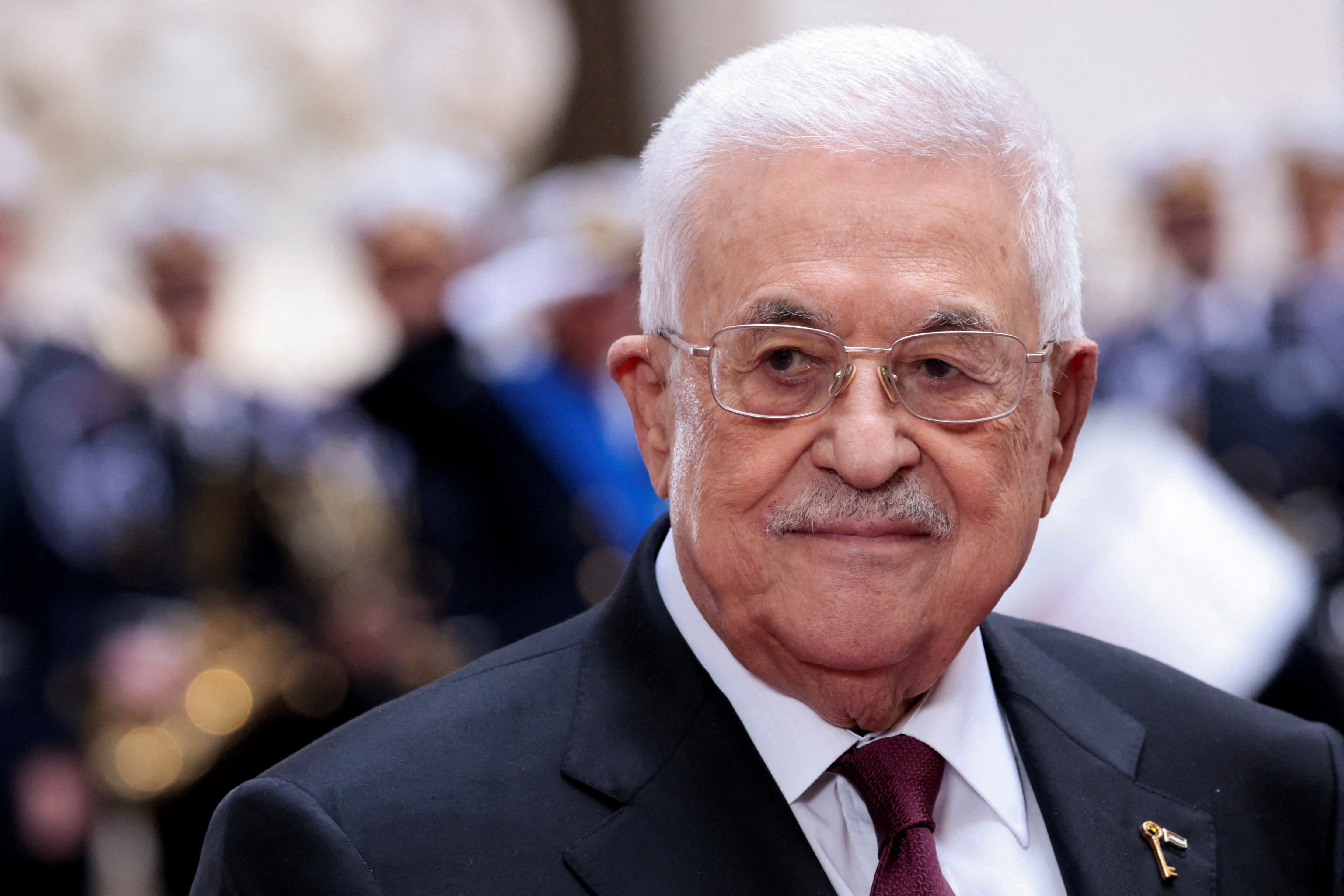 A headshot of Mahmoud Abbas wearing a black suit against a blurred background.
