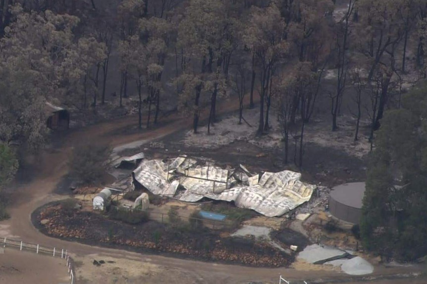 A property that has been flattened by the Wooroloo bushfire is surrounded by burnt trees and scrub.