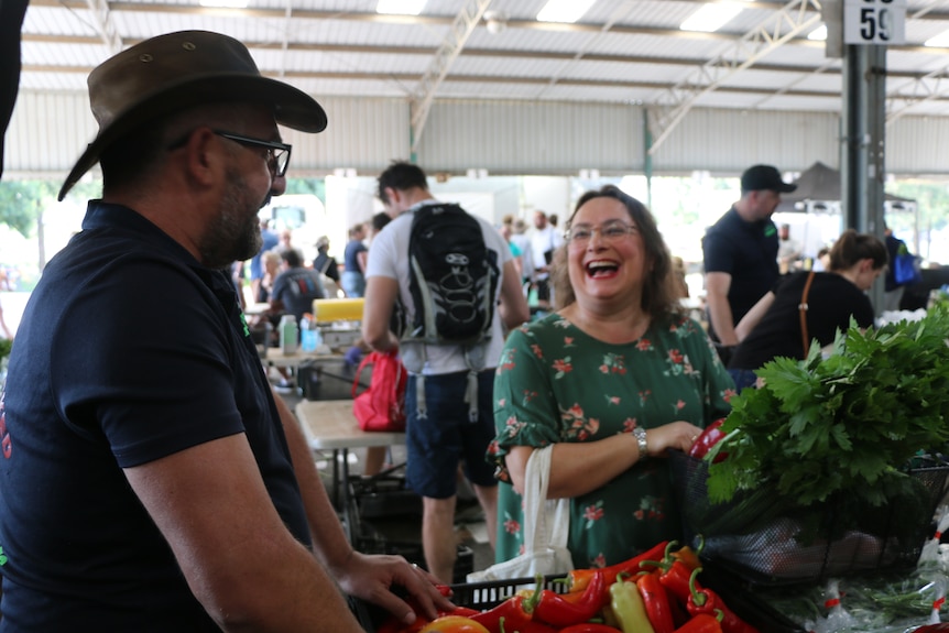 A man and a woman smile while examining produce.