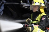 A female NSW firefighter battles a fire.
