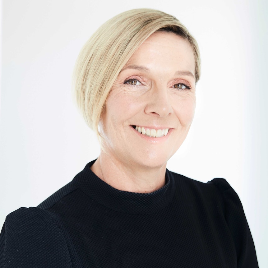 Close up of a woman with short blonde hair wearing black.