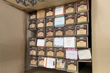 A cupboard full of cardboard boxes, containing music rolls which play in a pianola.