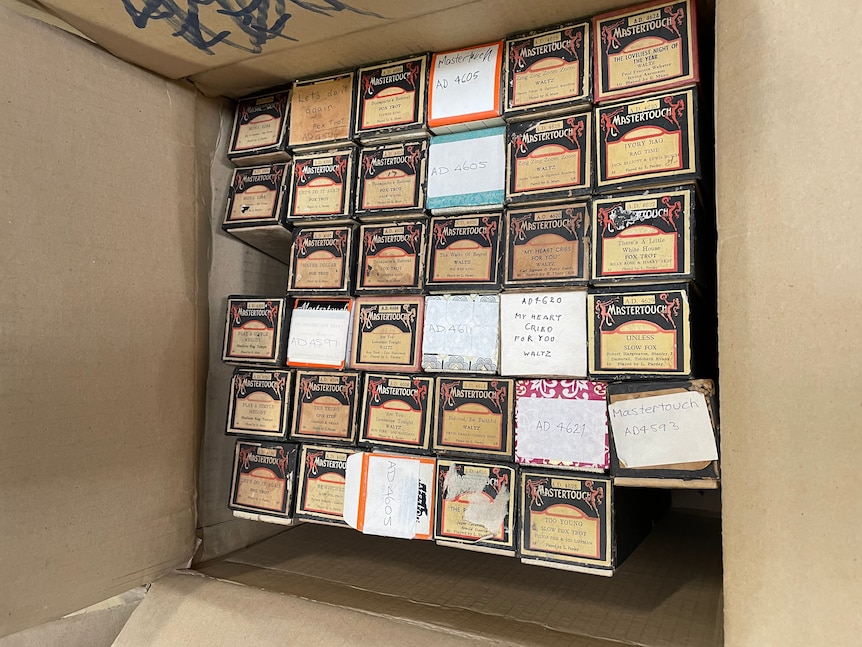 A cupboard full of cardboard boxes, containing music rolls which play in a pianola.