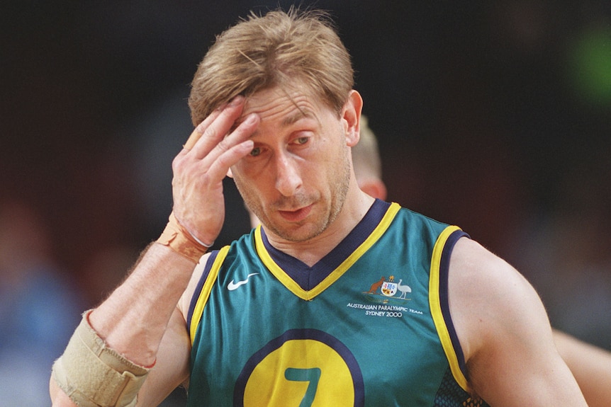 An Australian male wheelchair basketball player touches his forehand with his right hand at the Sydney Paralympics.