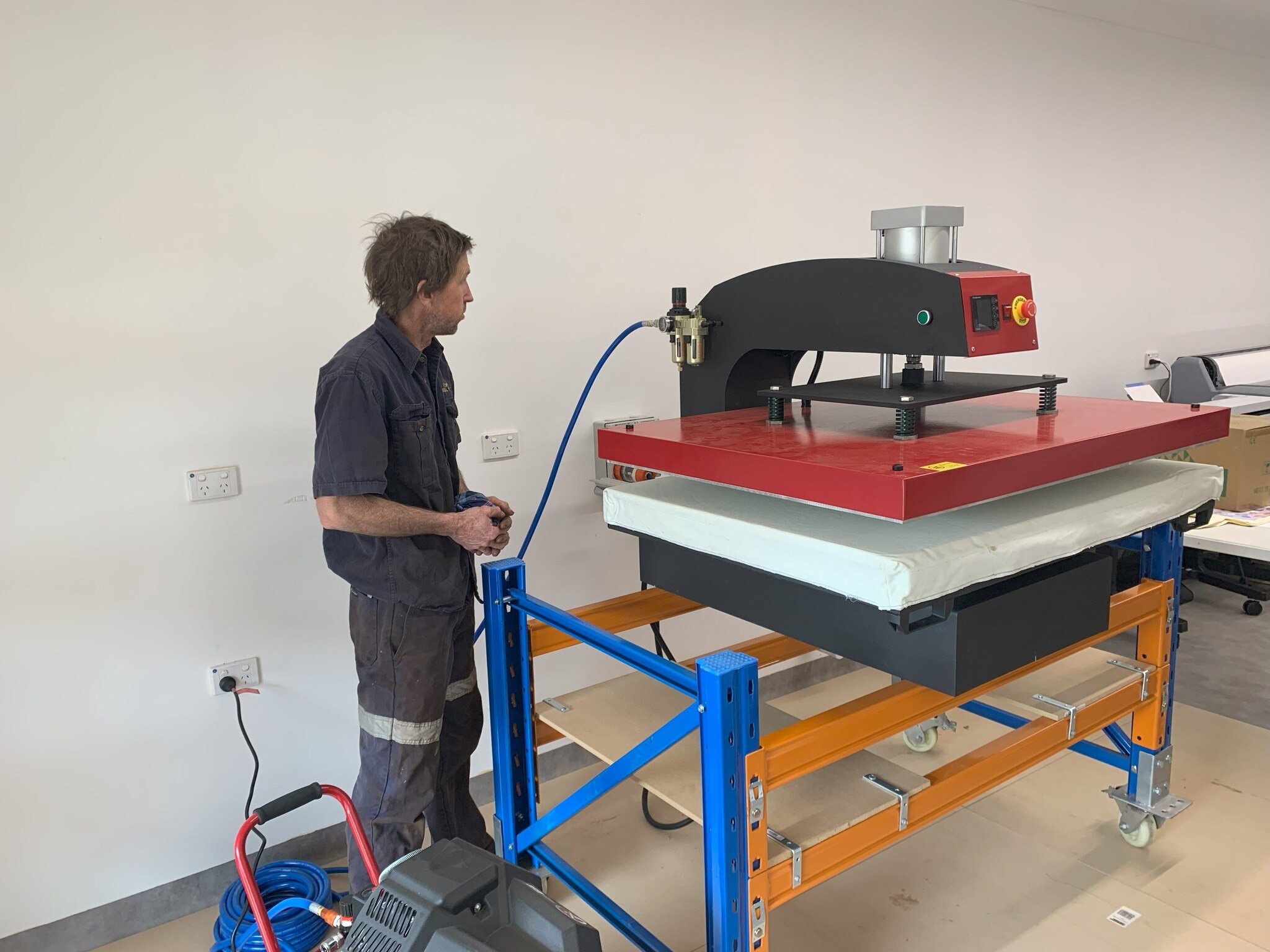 Tradie standing next to a big metal machinery. 