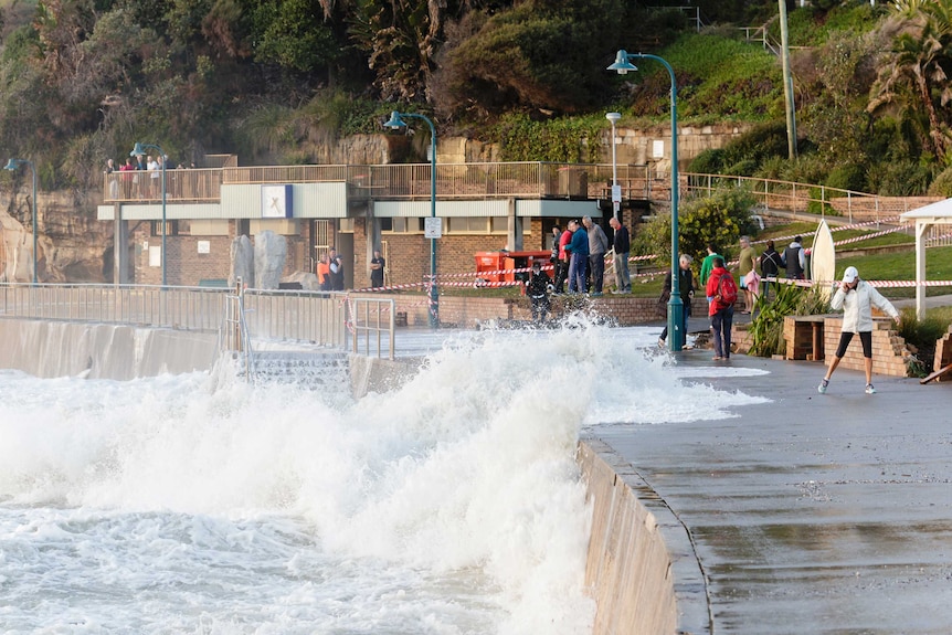 A high tide washes over a walkway on Sydney's coast.