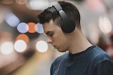 A man listening to audio on headphones and looking at his phone.