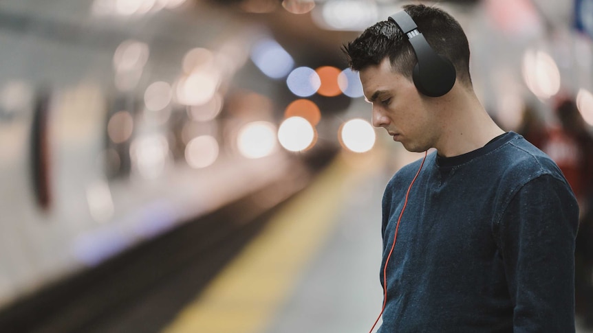 A man listening to audio on headphones and looking at his phone.