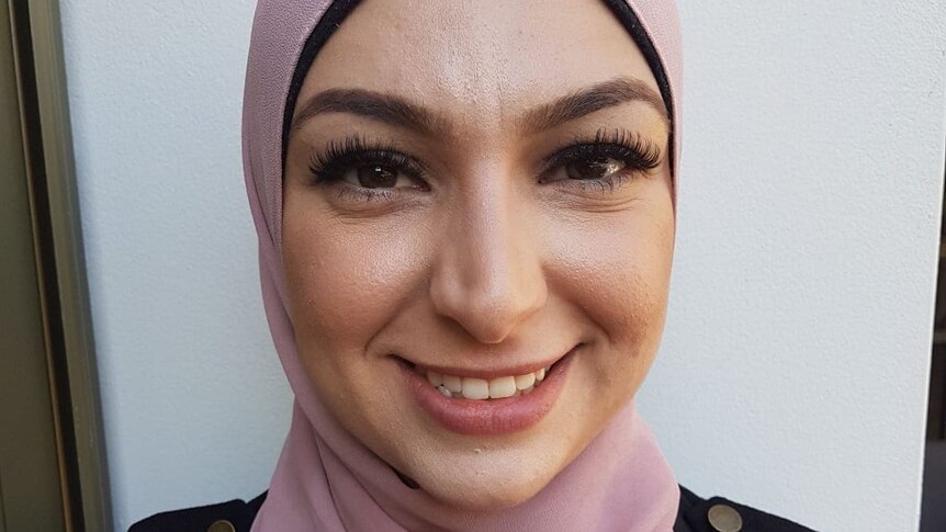 A smiling woman in a pink hijab