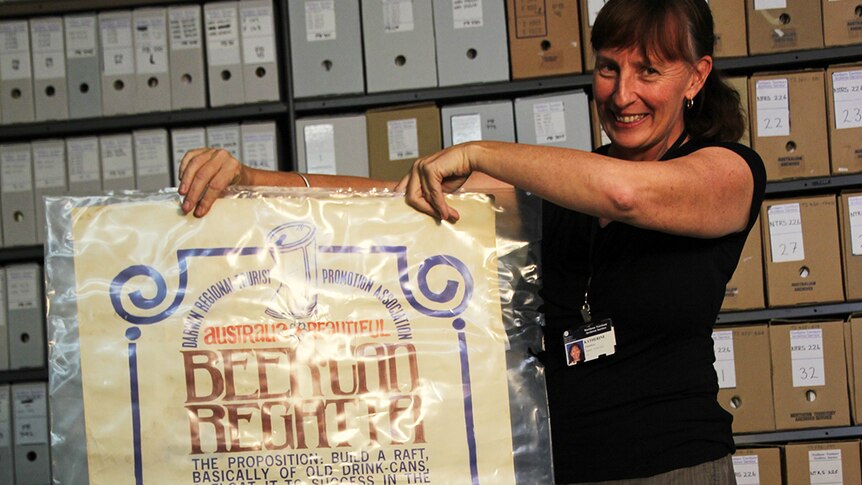 A photo of Archives officer Katherine Hamilton holding up a poster from 1974.