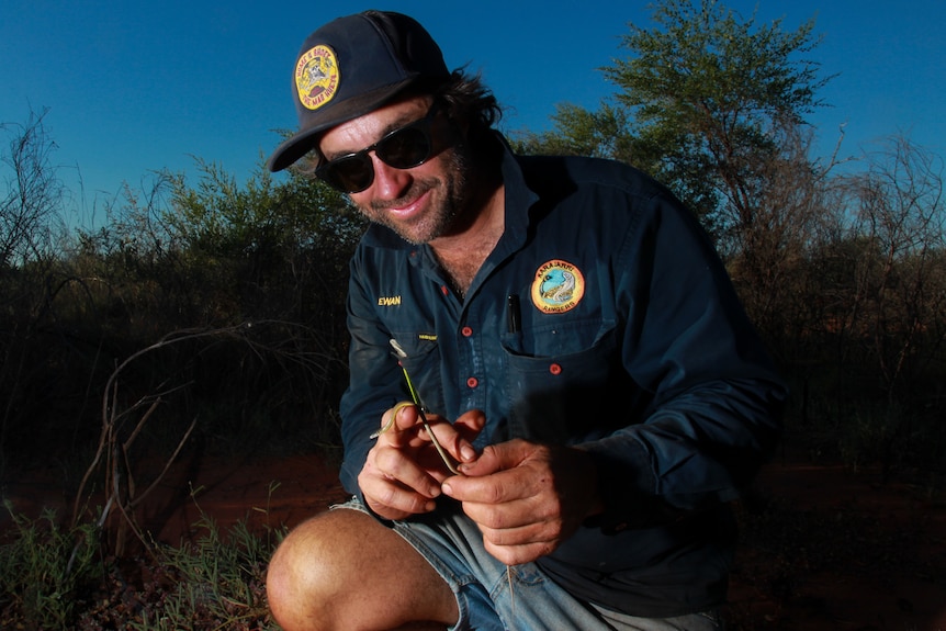 A man holding a small lizard.