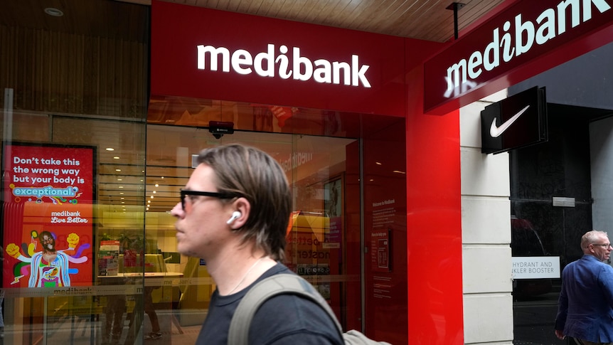 A man walks past a Medibank building. 