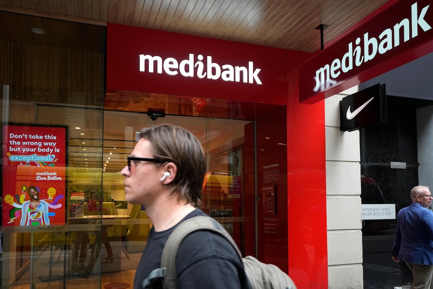 A man walks past a Medibank building. 