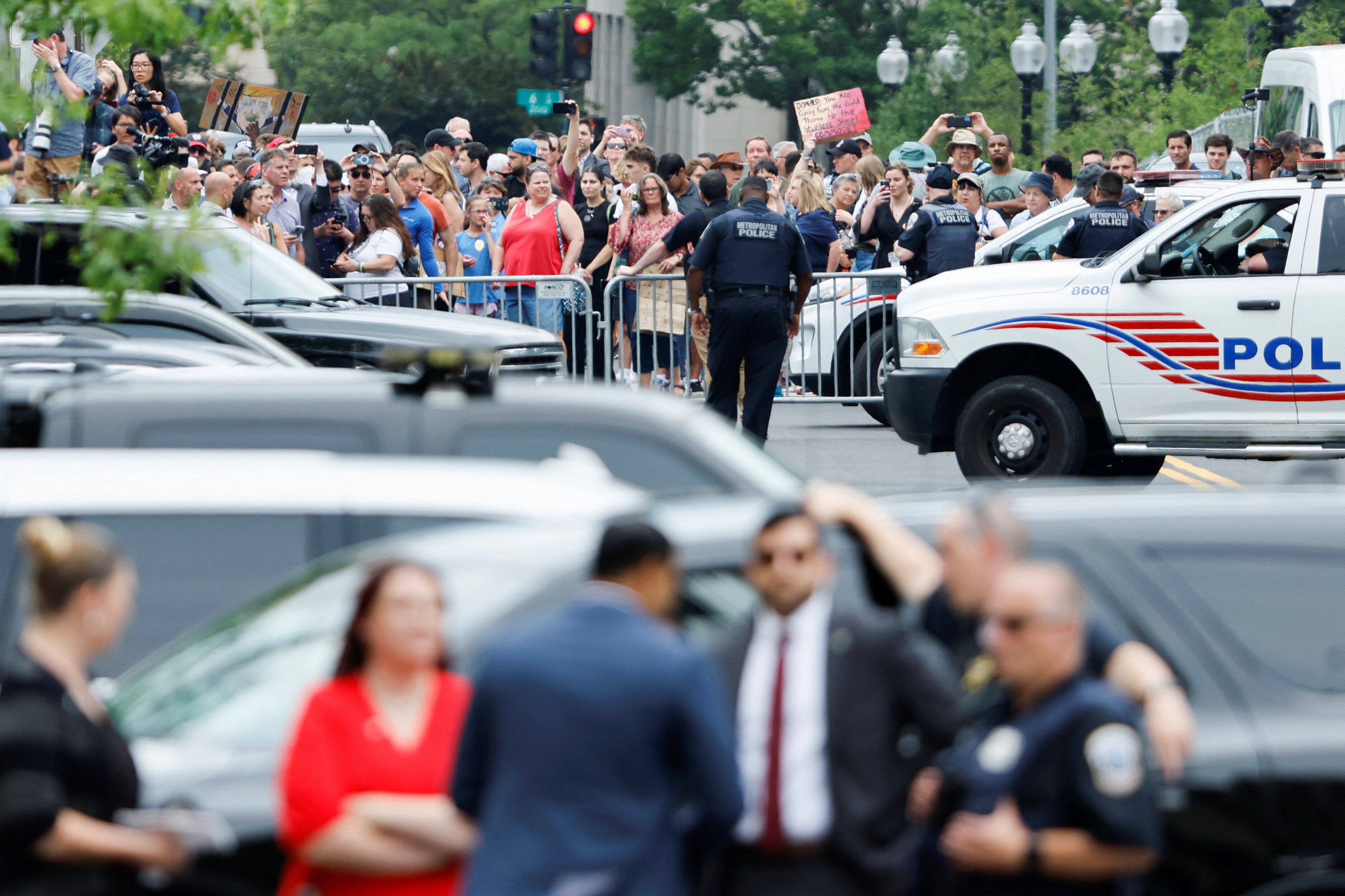 Police and officials in front of a barricade holding back protesters.