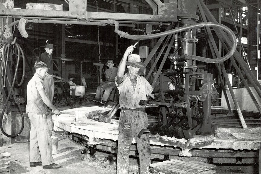 矿工们在一个巨大的齿轮附近工作。