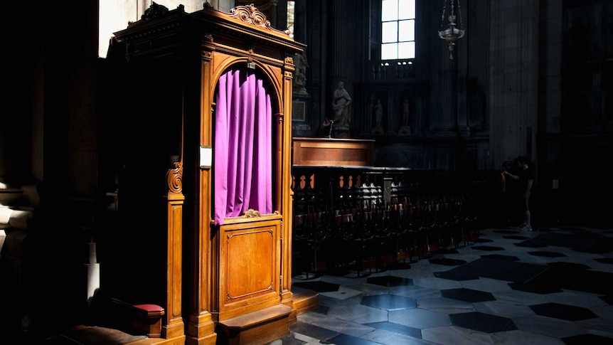 Wooden confession booth with purple curtain, in Catholic church.