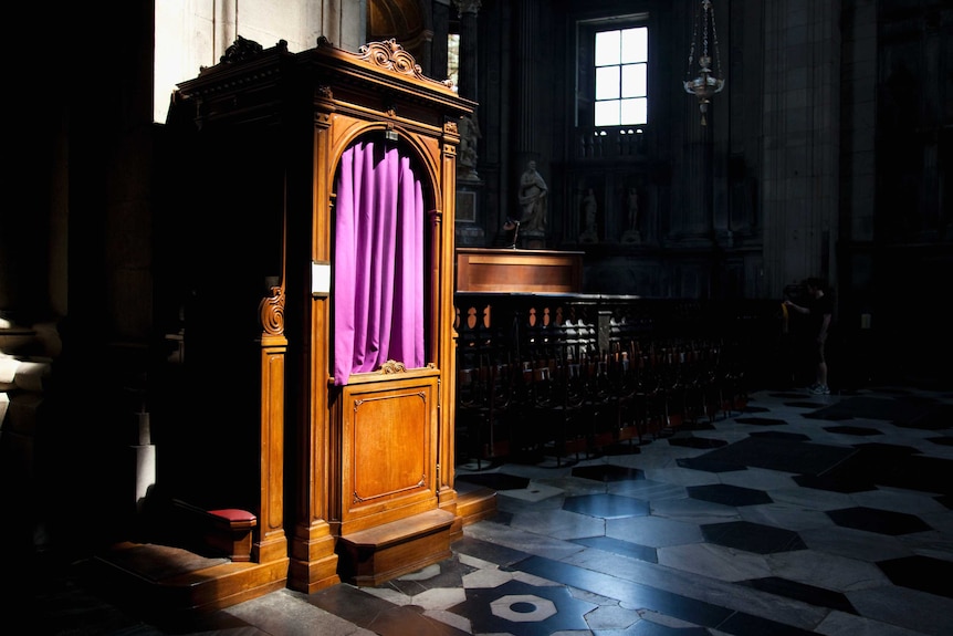 Wooden confession booth with purple curtain, in Catholic church.