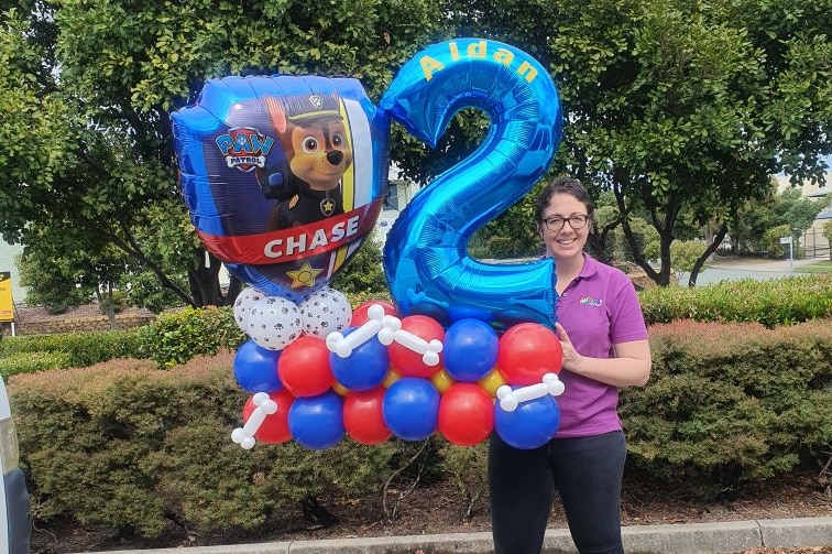 A woman holds a display made up of helium balloons.