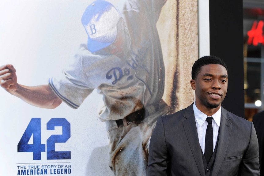 Actor Chadwick Boseman smiles at a film premiere he is wearing a suit