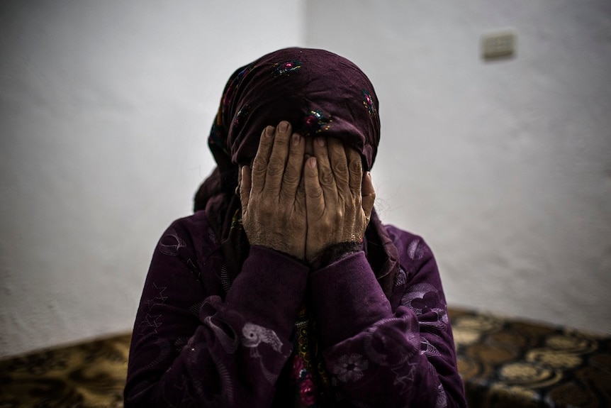 A woman dressed in purple hides her face