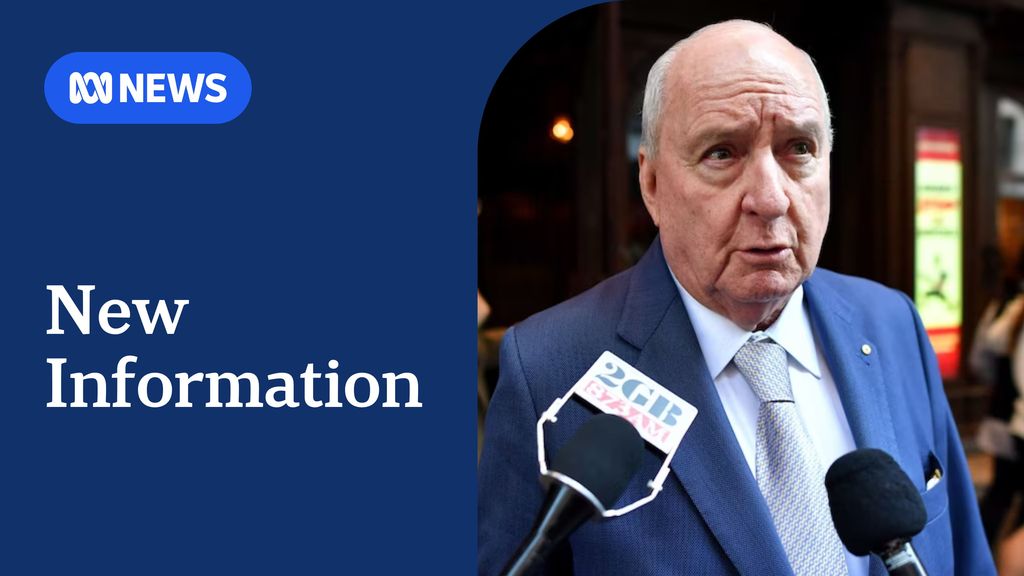 New Information: Alan Jones wearing a blue suit and silver tie speaking into two microphones held up to him by unseen people.