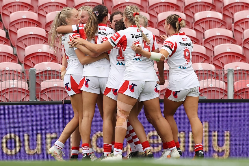 A group of St George Illawarra NRLW players celebrate a try.