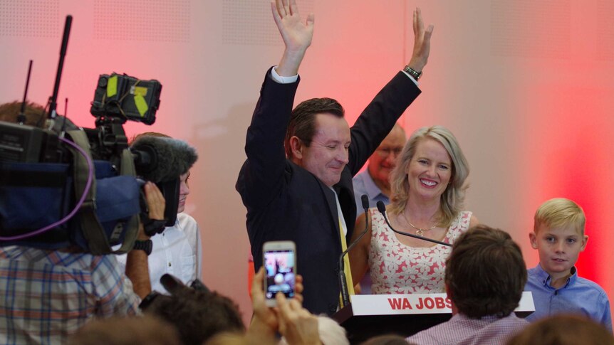 Mark McGowan throws his hands in the air at the podium where he makes his victory speech.