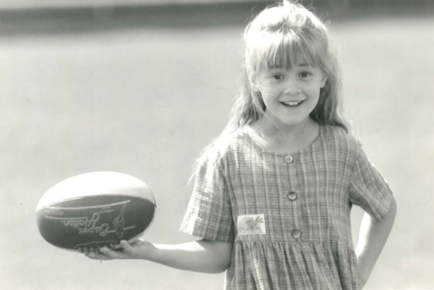 A photo of Clare Milne, Sylvia's daughter as a young child holding a football.