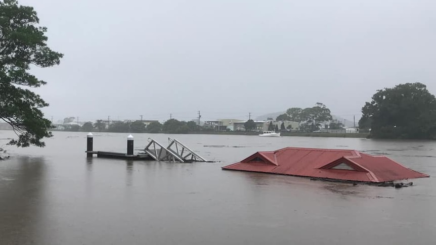 the roof of a building protrudes from floodwaters