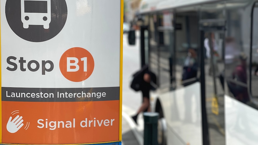 A sign shows a bus stop at the Launceston interchange. A bus is out of focus in the background.