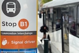 A sign shows a bus stop at the Launceston interchange. A bus is out of focus in the background.